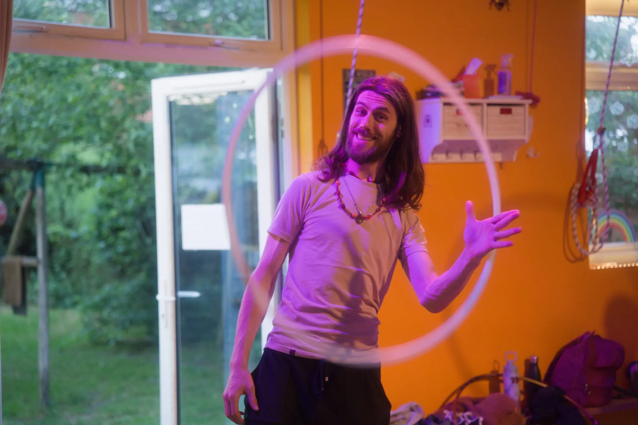 Hooper spinning a hoop around his hand in a bright, orange-walled studio