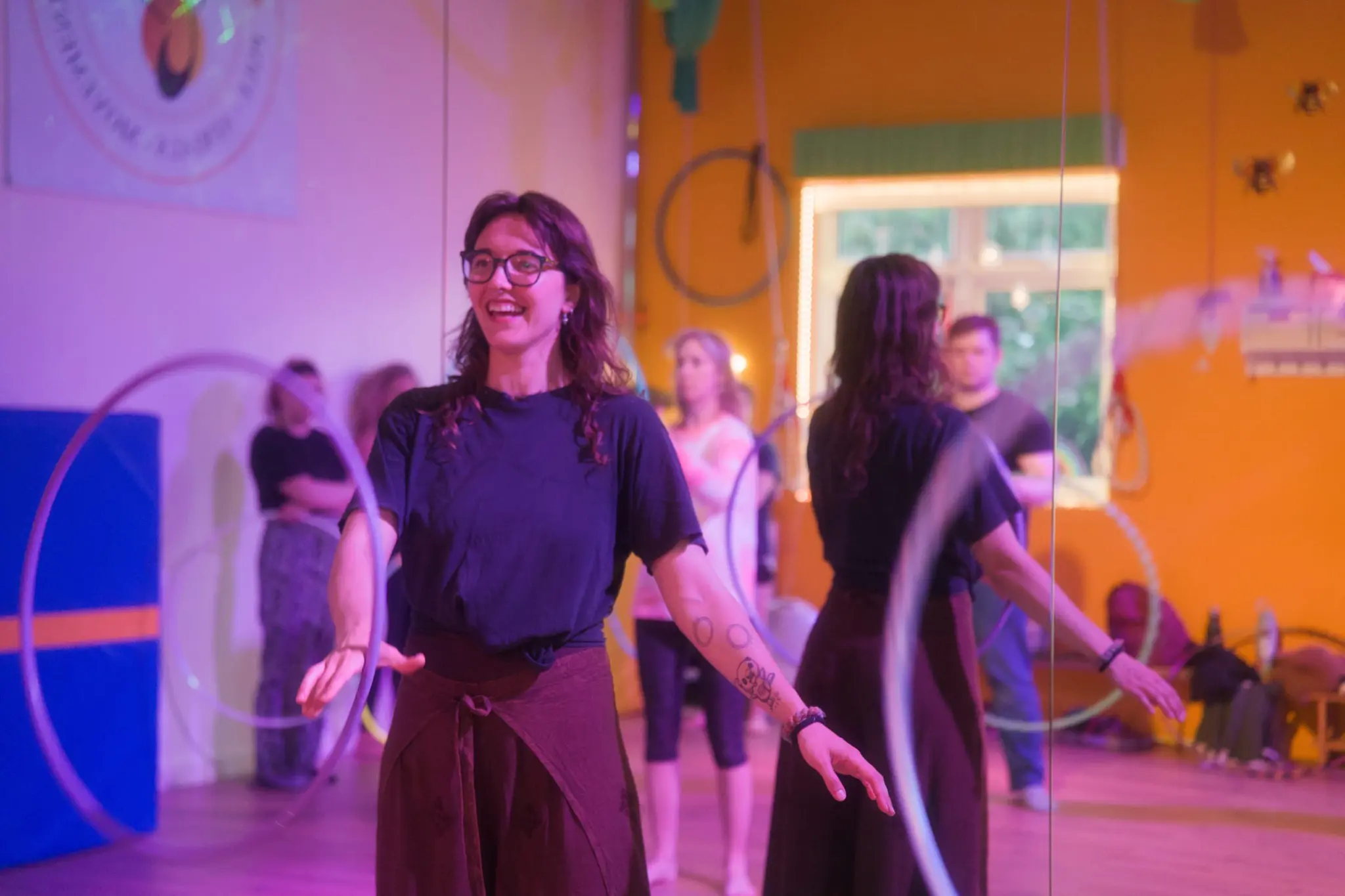 Osha smiling during a relaxed, beginner-friendly Flowsha hoop class