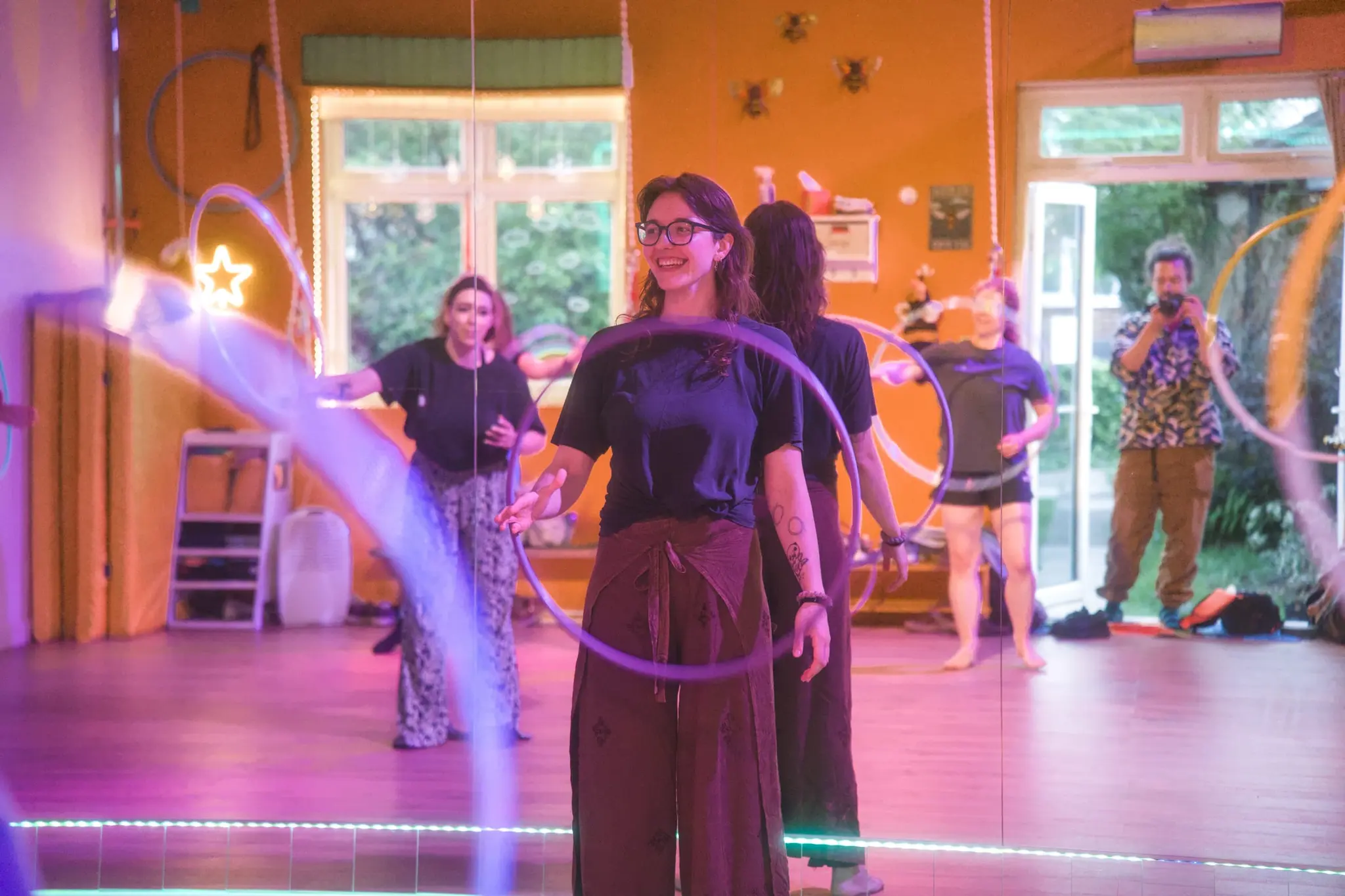 Osha smiling as she demonstrates a hoop move during a Flowsha class