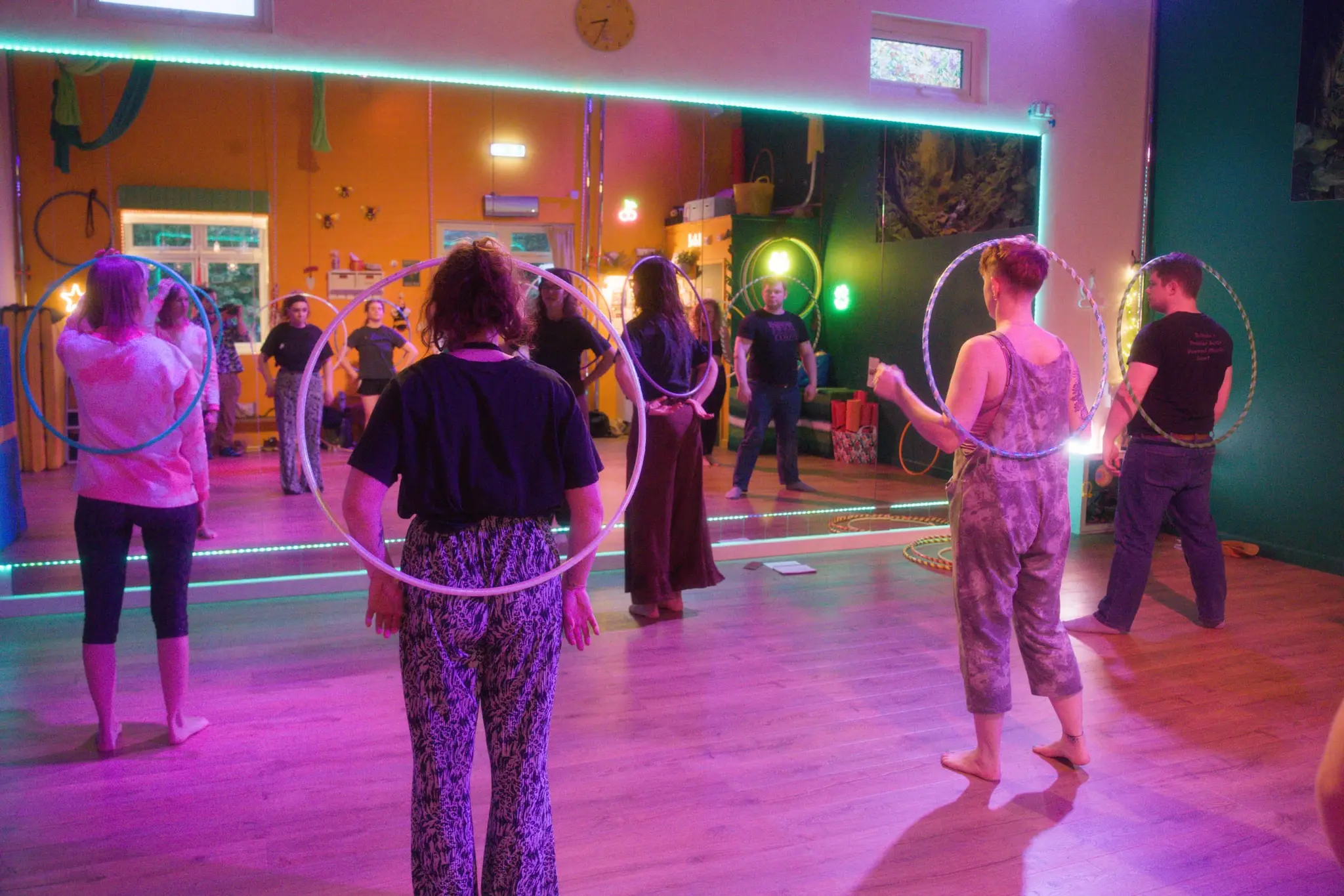 Circle of hoopers mid-flow under colourful studio lighting